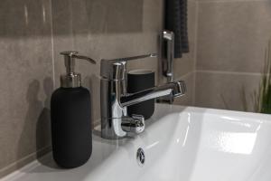 a bathroom sink with a soap dispenser next to a faucet at Isla Homes - Suite, Supermarket & Alko in Tampere