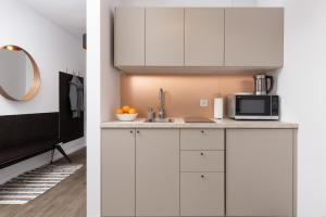 a kitchen with white cabinets and a microwave at Śląska Studio with Parking & Gym Business District Gdańsk by Renters in Gdańsk