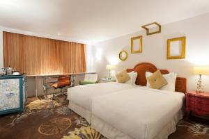 una camera d'albergo con due letti e una televisione di The Luxe Manor a Hong Kong