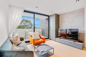 een woonkamer met een bank en een televisie bij Luxurious Elsternwick Apt Living with Parking in Melbourne