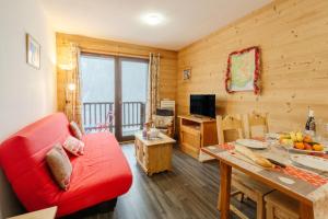 uma sala de estar com um sofá vermelho e uma mesa em Le Petit Bonheur em Modane