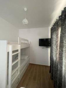 um quarto com prateleiras brancas e uma televisão e uma cortina em Holiday Home em Durrës