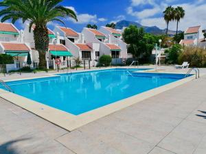 a swimming pool at a resort with palm trees and houses at The Good Life Holiday Home in Adeje