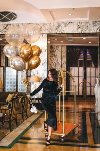 a woman in a black dress holding a bunch of gold balloons at Esplanade Zagreb Hotel in Zagreb