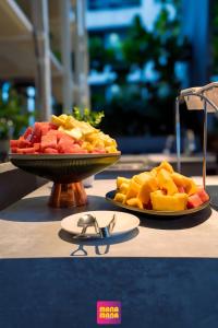 two plates of fruit sitting on a table with a pair of glasses at Ceylonz Suites KLCC Rooftop Infinity Pool KL Tower View in Kuala Lumpur