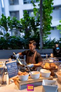 a man in an apron preparing food on a table at Ceylonz Suites KLCC Rooftop Infinity Pool KL Tower View in Kuala Lumpur +70 photos
