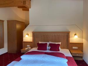 a bedroom with a large bed with two red pillows at Alp Resort Tiroler Adler in Sölden