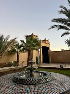 a fountain in front of a building with palm trees at Kasbah des cyprès in Skoura