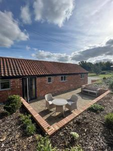 a patio with a table and two chairs and a building at The Calf Shed - cozy cottage in peaceful Norfolk countryside in Aldeby