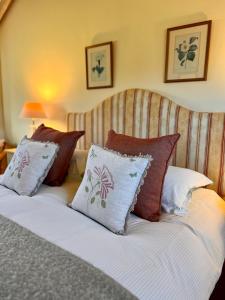 a bed with several pillows on top of it at The Calf Shed - cozy cottage in peaceful Norfolk countryside in Aldeby