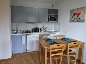 a kitchen with a wooden table with chairs and a kitchen with white appliances at Horizon Pelvoux Accueillant T2 pied des pistes in Puy-Saint-Vincent