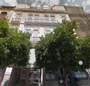 un edificio alto y blanco con árboles delante en Apartamento Tendillas, en Córdoba