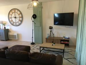 a living room with a couch and a tv at Le N5 des Hauts de Sarlat Apt Duplex Clim, Piscine, Parking in Sarlat-la-Canéda