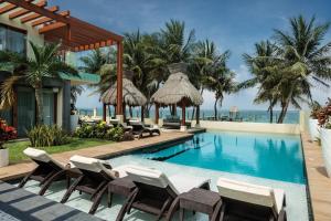 a resort with a swimming pool with chairs and the ocean at Azul Villa Esmeralda - Gourmet All Inclusive by Karisma in Puerto Morelos