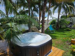 a hot tub in a backyard with palm trees at Un petit coin de paradis à La Réunion in Saint-Joseph