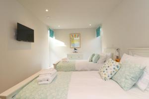 a bedroom with two beds and a flat screen tv at Stylish estuary view apartment in Padstow