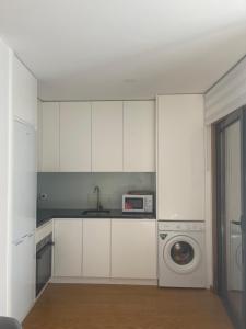 a kitchen with white cabinets and a washing machine at Cozy & Modern apartment in Porto in Porto