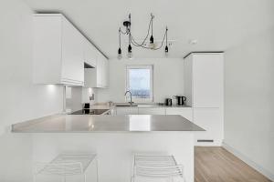 een witte keuken met een wastafel en een aantal stoelen bij Radiant Chelsea Flat with City View in Londen