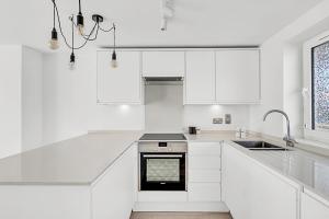 een witte keuken met witte kasten en een wastafel bij Radiant Chelsea Flat with City View in Londen
