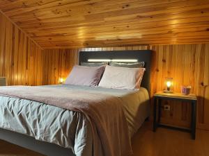 1 dormitorio con 1 cama con paredes de madera y suelo de madera en La Manou, esprit bois avec piscine privee, en Saint-Aulaire