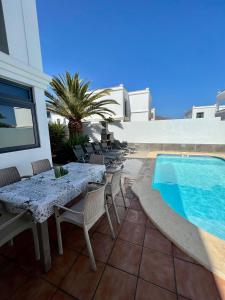 een patio met een tafel en stoelen naast een zwembad bij Villa Margherita in Playa Blanca