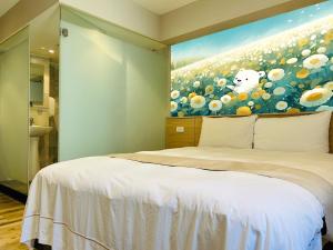 a bedroom with a bed with a painting on the wall at Dazz Inn in Taichung