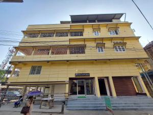 a woman with an umbrella walks past a yellow building at Hotel Hari Gayatri Regent in Guwahati