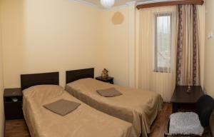 two beds in a small room with a window at Guest House LEADER in Ijevan