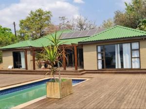 a house with a green roof and a swimming pool at Tshifaro Gardens in Thohoyandou