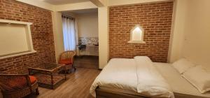 sypialnia z łóżkiem i ceglaną ścianą w obiekcie Hiti fusa w mieście Patan