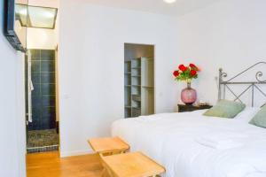a bedroom with a white bed and a vase of flowers at Appartement Centre-ville spacieux, élégant / Climatisation in Montpellier
