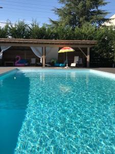 una gran piscina azul con sombrilla y un patio en Villa Lysa, Piscine privee, Coeur de ville, en Figeac