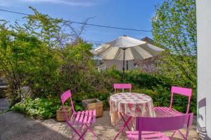 una mesa con sillas rosas y una sombrilla en Villa Lysa, Piscine privee, Coeur de ville, en Figeac