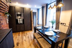 ein Esszimmer mit einem schwarzen Tisch mit Tellern und Weingläsern in der Unterkunft VIP - 2 BR Grade 2 Luxury Industrial House with Log Burning FIRE & electric blinds in the Heart of the JQ in Birmingham