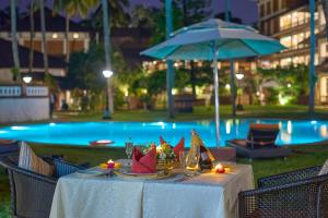 a table with napkins on it in front of a pool at The Raviz Kadavu, Kozhikode in Kozhikode