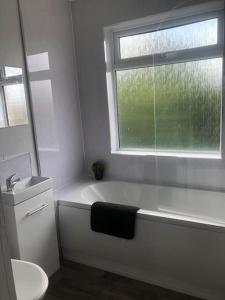 a white bathroom with a bath tub and a window at Highfield House cosy 4 bedroom in Scunthorpe