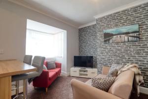 a living room with a red couch and a brick wall at Highfield House cosy 4 bedroom in Scunthorpe