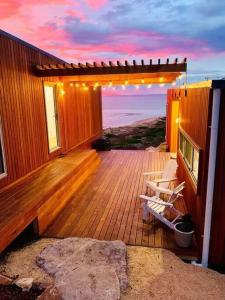 a wooden deck with two chairs sitting on it at Three Little Birds at Freycinet in Coles Bay