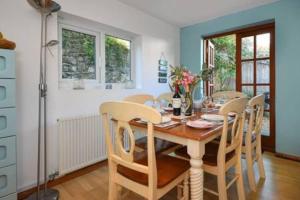 a dining room with a wooden table and chairs at Beautiful cottage a stones throw from the beach. in Llanbedrog