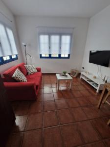 Casa Calandrilla في Caleta de Caballo: غرفة معيشة مع أريكة حمراء وتلفزيون