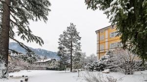 a building covered in snow next to a yard at Hotel Jarolim in Bressanone