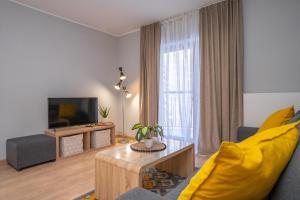 a living room with a yellow couch and a television at RentPlanet - Studio Górna Resorts in Szklarska Poręba