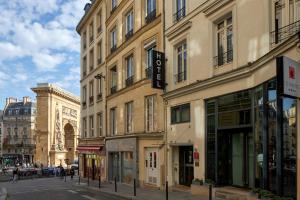 un bâtiment dans une rue où les gens marchent dans la rue dans l'établissement Hotel Les Théâtres, à Paris