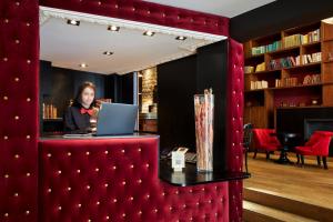 a woman sitting at a desk with a laptop at Hotel Les Théâtres in Paris