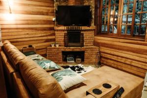 un salon avec un canapé et une cheminée dans l'établissement Chalé São Bernardo - banheira de hidromassagem privativa, à Paiol Grande