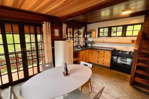 Il comprend une cuisine équipée d'une table blanche et d'un réfrigérateur blanc. dans l'établissement Chalé São Bernardo - banheira de hidromassagem privativa, à Paiol Grande