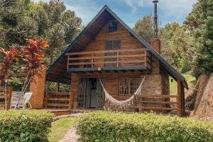 une cabane en rondins avec un hamac en face de celle-ci dans l'établissement Chalé São Bernardo - banheira de hidromassagem privativa, à Paiol Grande