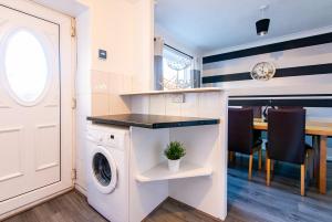 a laundry room with a washer and a table at Redcroft Green - Modern 3 bedroom house in Kenton