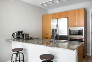 a kitchen with a stainless steel refrigerator and two bar stools at Streeterville 1br w terrace gym nr riverwalk CHI-997 in Chicago
