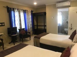 Habitación de hotel con 2 camas y TV en Pratap Palace, en Chittorgarh